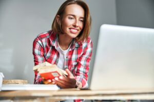 Portrait of a merry female with building materials made of wood leaning towards the laptop